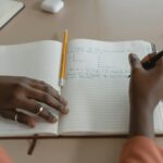 person writing budget notebook
